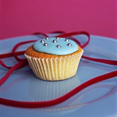 Cupcake with blue icing, silver dragees and velvet ribbon