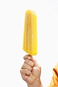 Hand holding an orange ice lolly