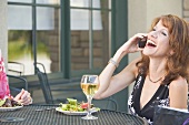 Brunette on phone at laid table on terrace