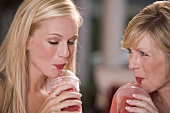 Young woman & mature woman drinking frozen strawberry smoothies