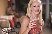 Young woman holding a beaker of frozen strawberry smoothie