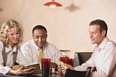 Three people at a restaurant table reading the menu