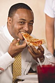 Mann beisst in ein Stück Pizza