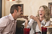 Frau füttert Mann mit Pizza im Restaurant