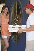 Junge Frau an der Haustür empfängt einen Pizzaboten