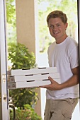 Man standing at house door with pizza boxes