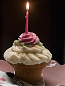 A cupcake with a burning birthday candle
