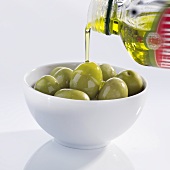 Olivenöl über Oliven gießen