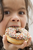 Girl biting into a doughnut with sprinkles