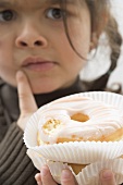 Girl with sceptical expression holding doughnut, one bite taken