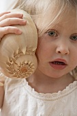 Girl listening to a shell in wonderment
