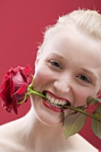 Young woman with a red rose in her mouth