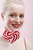 Young woman holding a heart-shaped lollipop