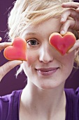 Young woman with two heart-shaped biscuits in front of her eyes