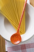 Spaghetti with cooking spoon on pile of plates