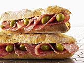 Zwei Baguettesandwiches mit Salami und Oliven
