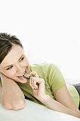 Young woman lying on a sofa eating chocolate