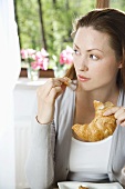 Young woman eating croissant