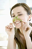 Young woman holding rocket leaf across her nose