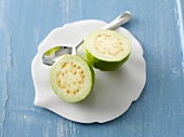 Halved guava with spoon on china plate