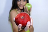 Young woman holding one red and one green apple