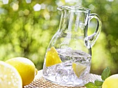 Glass jug of mineral water with lemon wedges and ice cubes