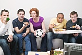 Freunde mit Fussball, Pizza und Bier sitzen vor dem Fernseher