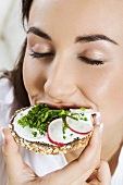Young woman eating open sandwich on wholemeal bread