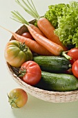 Fresh tomatoes, cucumbers, carrots & lettuce in small basket