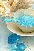 Blue bath salts, glass pebbles and coral