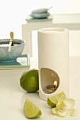 Scented lamp with limes, orchid flower and bowl of tea