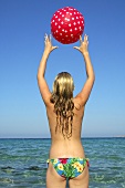 Frau spielt mit einem Wasserball im Meer