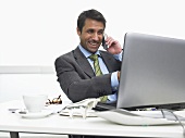 Businessman on telephone pointing at computer screen