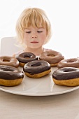 Little girl sitting in front of a plate of doughnuts