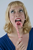 Blond woman licking a candy cane