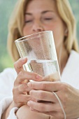 Woman in white bathrobe holding a glass of water