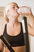 Blond woman drinking mineral water during workout
