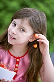 Girl holding pair of cherries to her ear