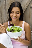 Young woman eating green salad