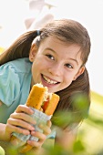 Girl eating fish and salad sandwich at picnic