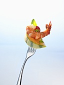 A piece of melon and a cooked prawn on a fork