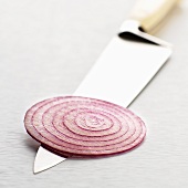 A slice of red onion on a knife