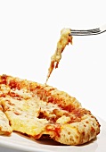 A slice of pizza with cheese strings on a fork