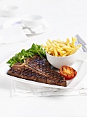 T-bone steak with chips and grilled tomatoes