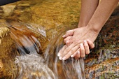 Frau hält ihre Hände in strömendes Wasser