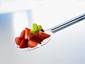 Several pieces of strawberry on a plastic spoon