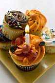Assorted muffins, one with birthday candle