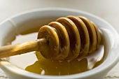 Honey dipper lying in a small bowl of honey