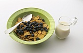 Cerealien mit frischen Heidelbeeren, Milch im Glaskrug