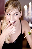 Young woman biting into shrimps on skewer